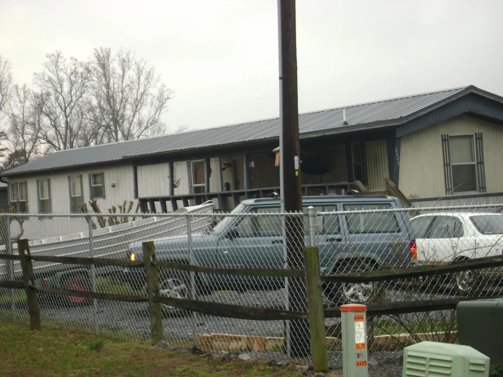 Dark metal roof on a long single story building behind a chain link fence in Rockledge