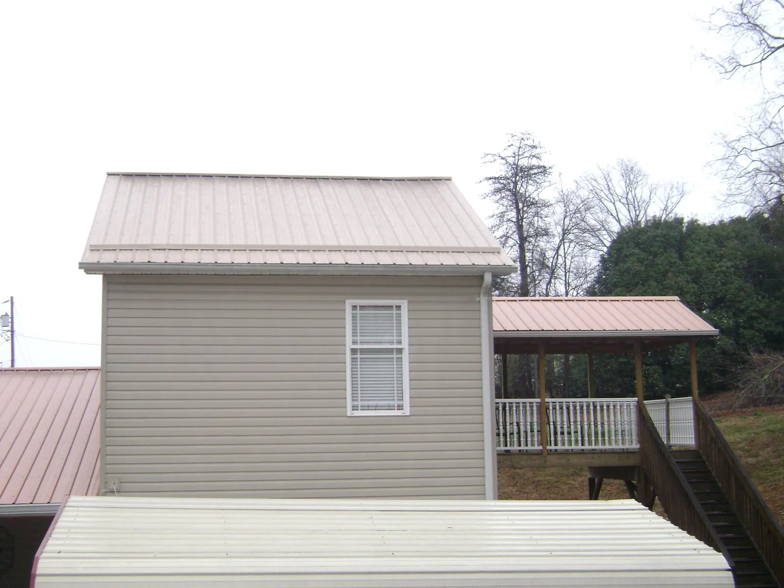 Tan metal roofs on a two story addition and attached porch, from a Roof Replacement job in Rockledge